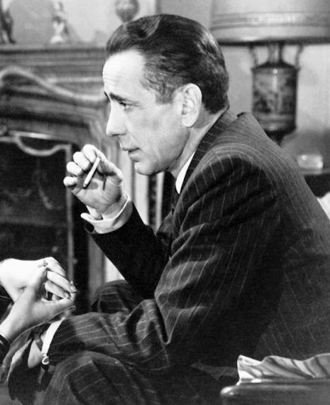 Humphrey Bogart in profile holding a lit cigarette near his face, 1947 Warner Bros. publicity still from Dark Passage