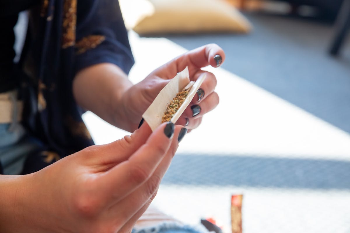 A person carefully rolling a cannabis joint on a tray